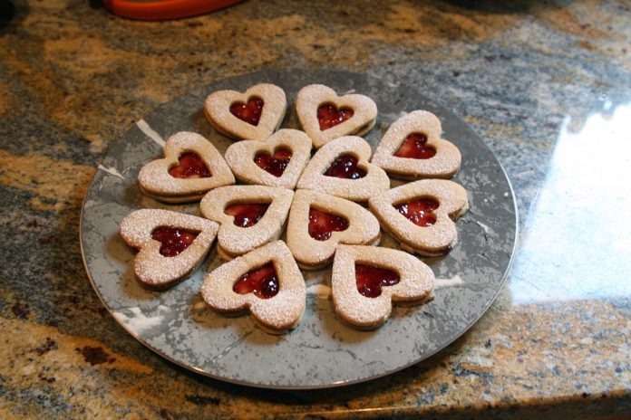 linzer-cookies A plate of heart shaped linzer cookies with raspberry filling.