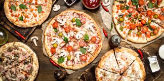 A variety of pizzas on a table as seen from above.