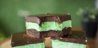 Three Chocolate Mint Brownies Stacked on a cutting board, showing the brownie, green filling layer and chocolate topping layer.