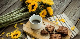 Cinnamon Brownies on a cutting board with a cup of coffee and sunflowers on the table.
