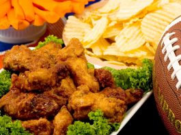Parmesan Wings with Super Bowl party snacks and a football in the background.
