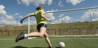 girl kicking soccer ball into goal