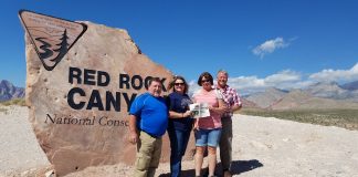 The Bates and Tracy Families pose in front of the entrance for Red Rock Canyon National Park with the Farm and Dairy paper in hand.