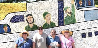 Joyce and John Paglialunga and their children, John and Jeana, stand in front of a mosaic wall depicting Fidel Castro and Guerrillero Heroico.
