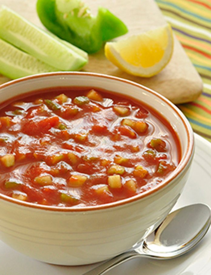 A bowl of Gazpacho Soup A bowl of Gazpacho Soup with lemon, green pepper and cucumber in the background