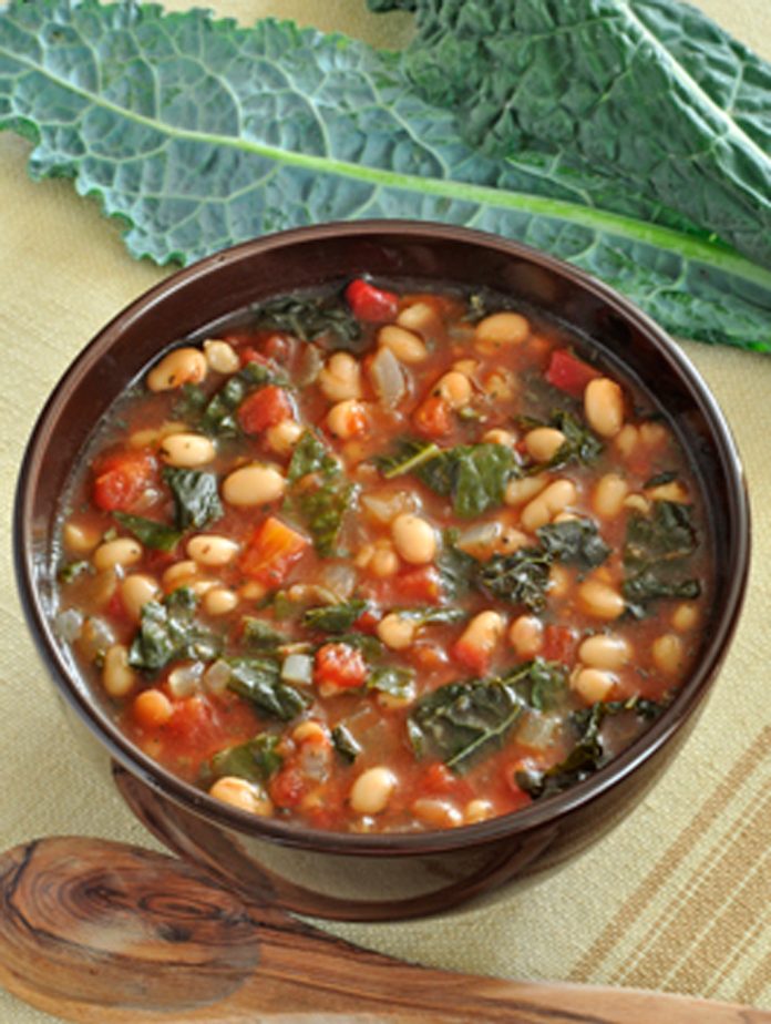 A bowl of Kale & White Bean Soup A bowl of kale and white bean soup with Kale leaves in the background.