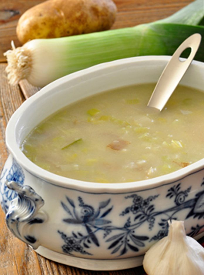A bowl of Creamy Potato Leek Soup A bowl of Creamy Potato Leek Soup, a leek and poato are in the background and a bulb of garlic is in the foreground