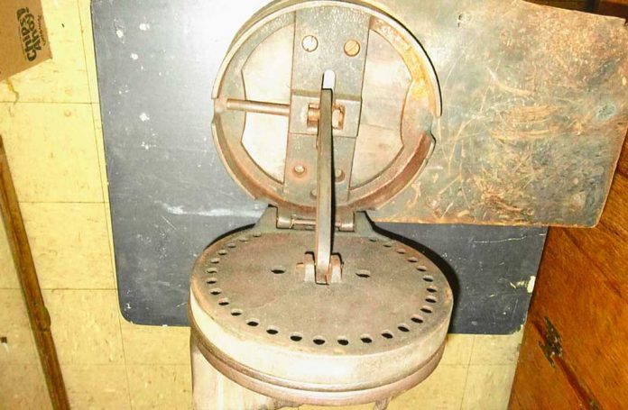 Item No. 1125 Richard Bader, of Middletown, New York, picked up Item No. 1125 at a yard sale. It is 9 inches in diameter, 6 1/2 inches in height when closed and weighs 12 pounds. There is a lever on the side that you can move to any hole on the disk. The peg on top has a handle and moves back and forth.