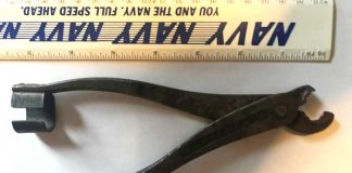 Metal plyer like item with a c-shaped piece on the end of one of the arms and curved pinchers that do not sit flat together.