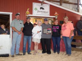 Darell Furlong stands with Ginny Barker and members of the hog committee after they recognized him with a plaque for his retirement.