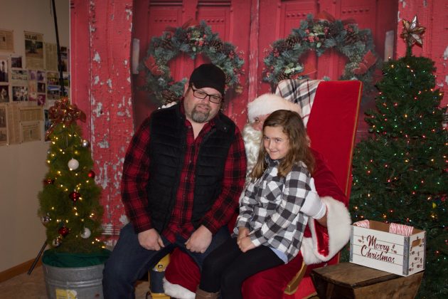 Avalynn Bloomfield and Richard Bloomfield, her dad, sit on Santa's lap together.