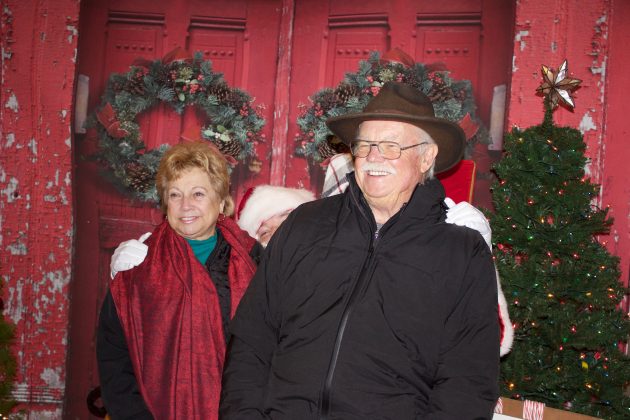 A couple sit on Santa's lap together.