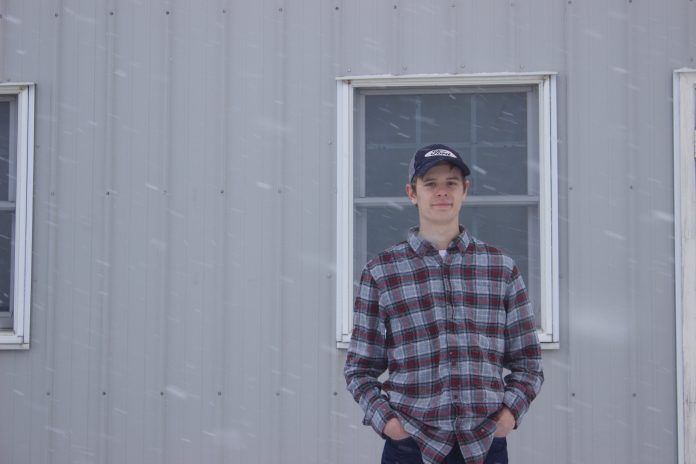 Baer_3 Michael Baer, 18, stands in front of a barn at Rogers Community Auction while it snows.