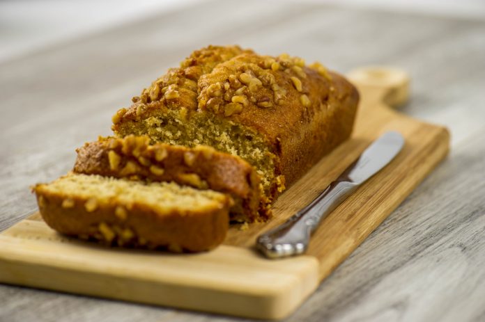feature.web Gluten-free banana bread loaf on a cutting block with a knife and two slices cut from the end.