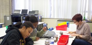 Two students and a teacher work on a soil experiment.