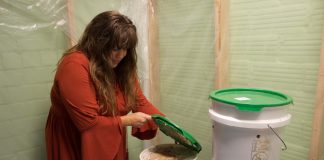 A woman lifts the lid on a bucket.