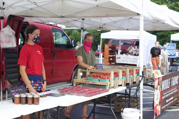 Two women work at a stand at a farmers market.