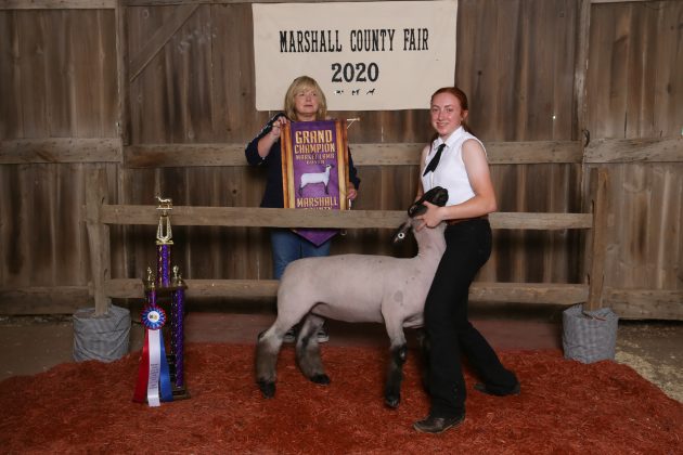 Two people stand with a lamb.