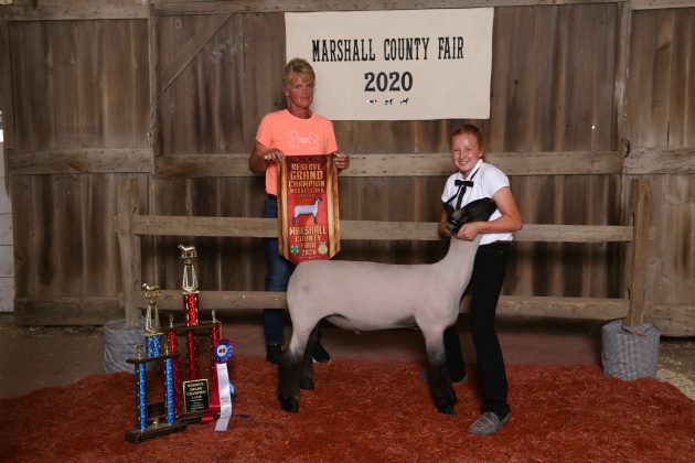Two people stand with a lamb.