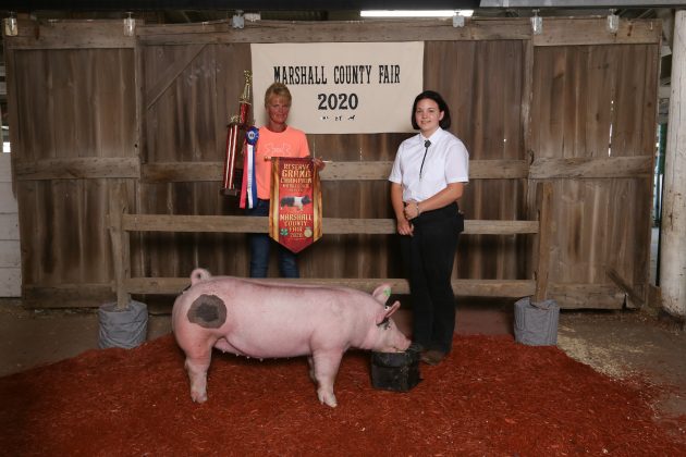 Two people stand with a hog.
