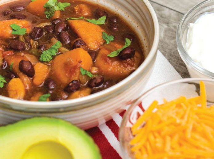 Bowl of Sweet Potato Chili with Avocado and Cheddar cheese on the side
