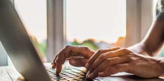 Hands type on a laptop.