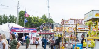 people walk up and down the midway at a fair.