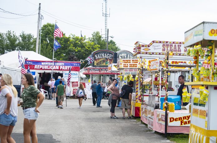 Canfield Fair people walk up and down the midway at a fair.
