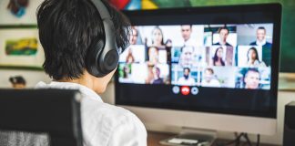 A person sits at a computer, video conferencing with multiple people.