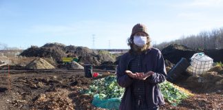 A man stands in front of a composting facility.