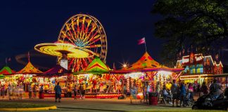 amusement rides and games with lights at a fair at night.
