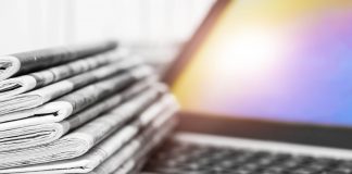 A pile of newspapers on a laptop.