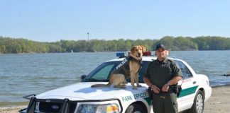 An ODNR officer and K-9 stand in front of a car.