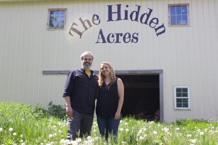 the_hidden_acres_4 A man and a woman stand in front of a barn with the words
