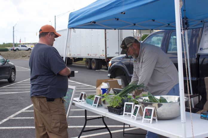 highlands_farmers_market_1 A farmer serves a customer at a farmers market.