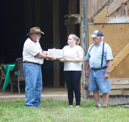 Madison McWilliams accepts an award from Bob Hendershot on behalf of her father, Harry Kenney, with her grandfather, also named Harry Kenney.