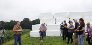 A farmer addresses a group of visitors at a farm tour.