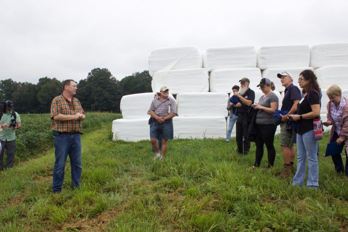 soil_health_tour A farmer addresses a group of visitors at a farm tour.