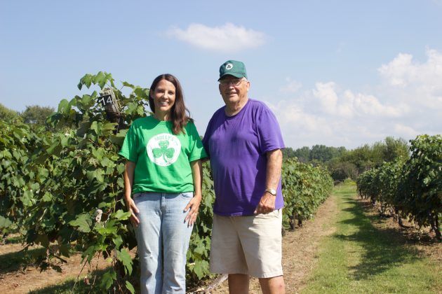 A woman and her dad stand in a vineyard.