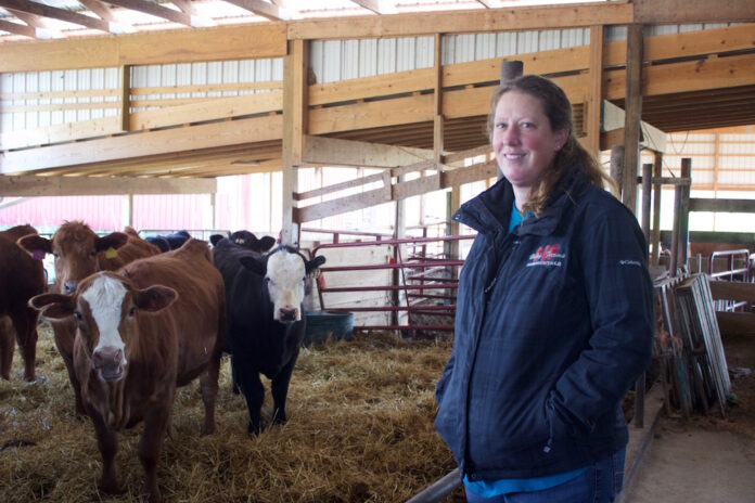 traceability_1 A woman stands near cows in a barn