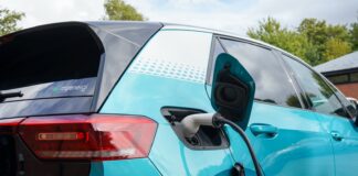 a charging cord is plugged into an electric car behind the rear passenger door