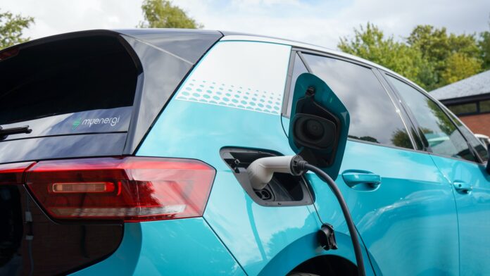 electric car a charging cord is plugged into an electric car behind the rear passenger door