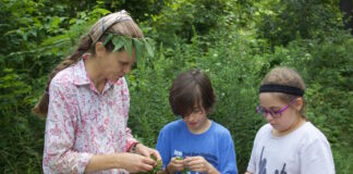 a woman and two children cutting up ingredients for a salad.
