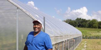a man stands next to a high tunnel