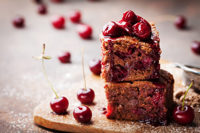 Chocolate brownie decorated with cherry. Homemade cake on wooden