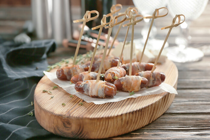 Wooden board with bacon wrapped dates on table