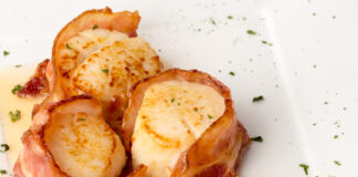 Bacon Wrapped Scallops on White Plate with Lemon Slices and Gree