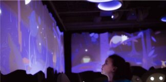 child looks at a blue interactive wall reflecting a water table