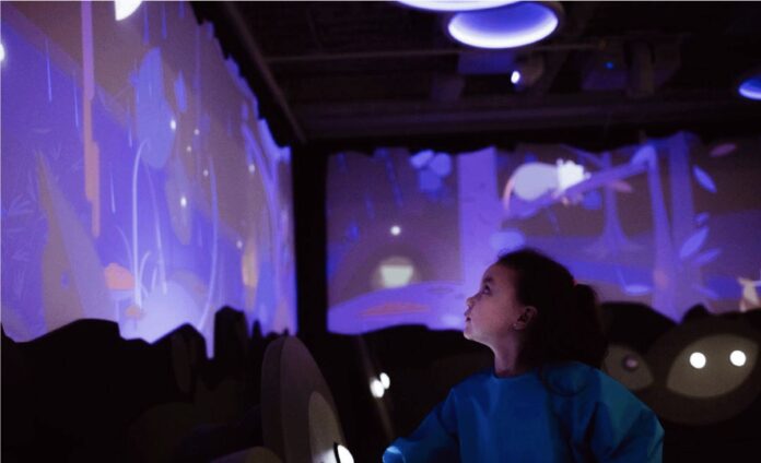 child digital wall featured child looks at a blue interactive wall reflecting a water table