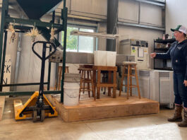 woman stands beside chestnut milling machine at Rural Action